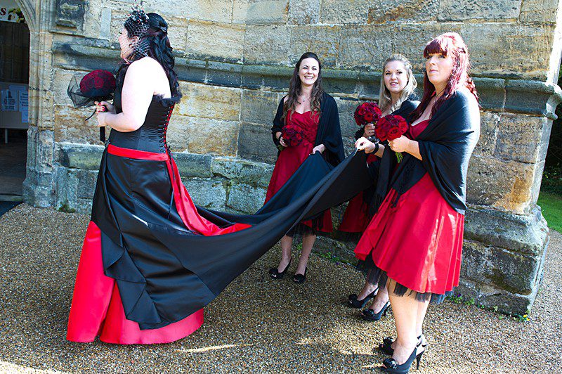 faye 2 alternative wedding dress with long black train and bridesmaids