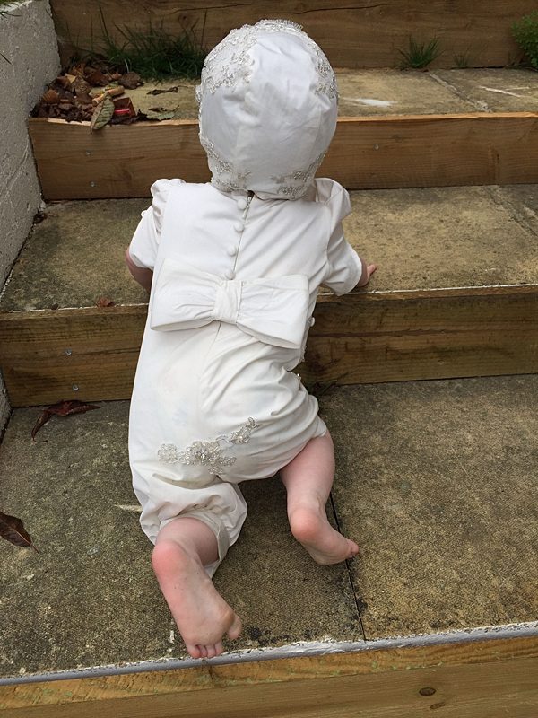 baby crawling up the steps, traditional romper all in one baby with bow and buttons cute bespoke christening