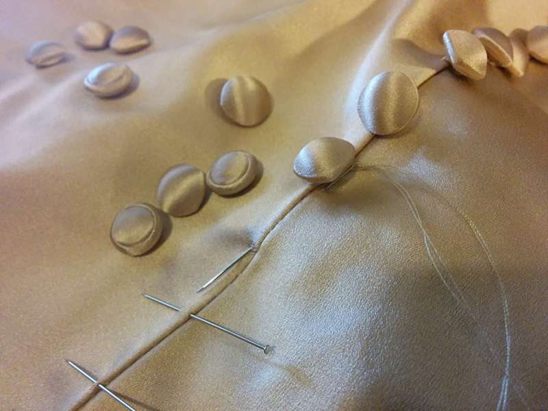 cover buttons being sewn on by hand