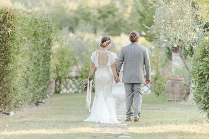 bride and groom hold hands in Italian countryside