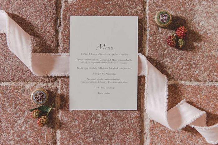 wedding menu flatlay with pink ribbon on tiles