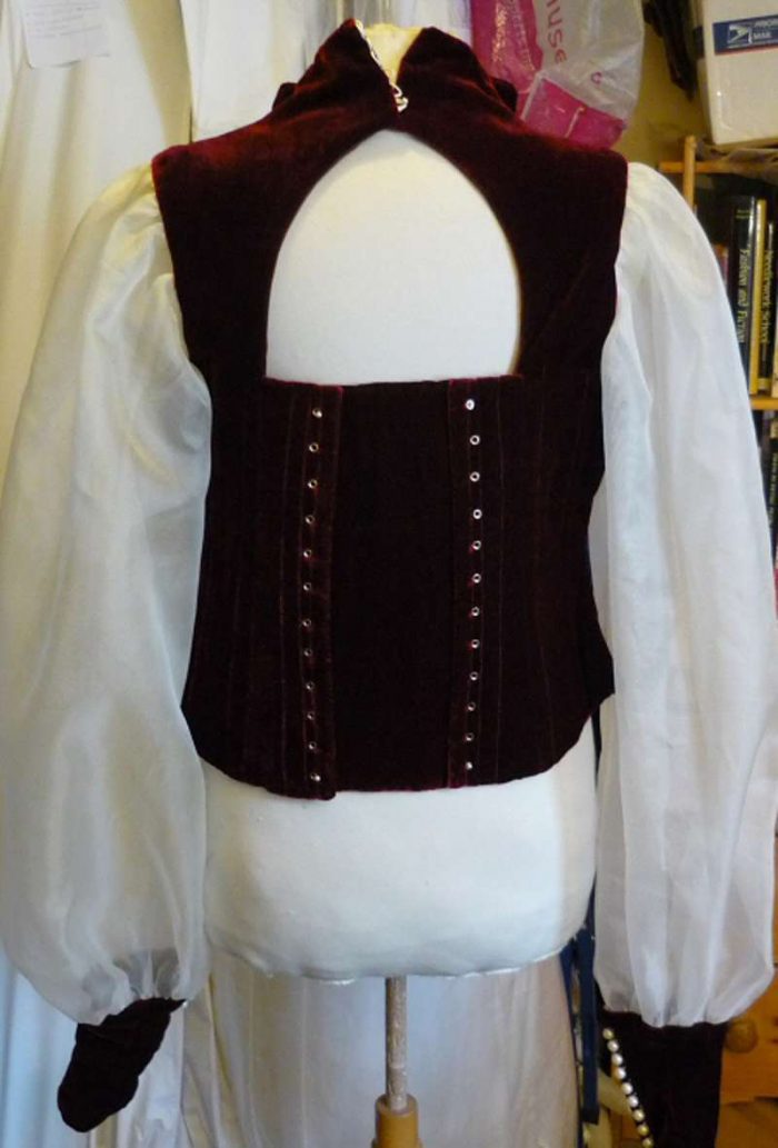 keyhole back for lace up red velvet bodice on the stand in the workroom