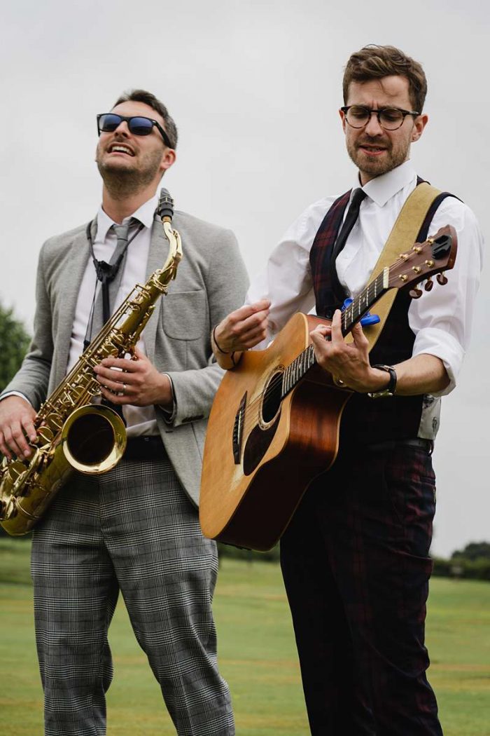 sax and guitar players on a lawn