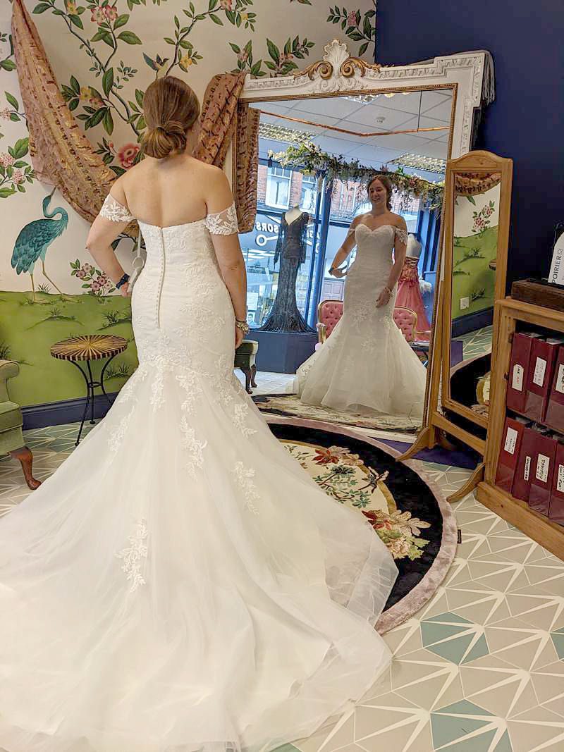bride views herself in a big mirror fitting room bridal shop