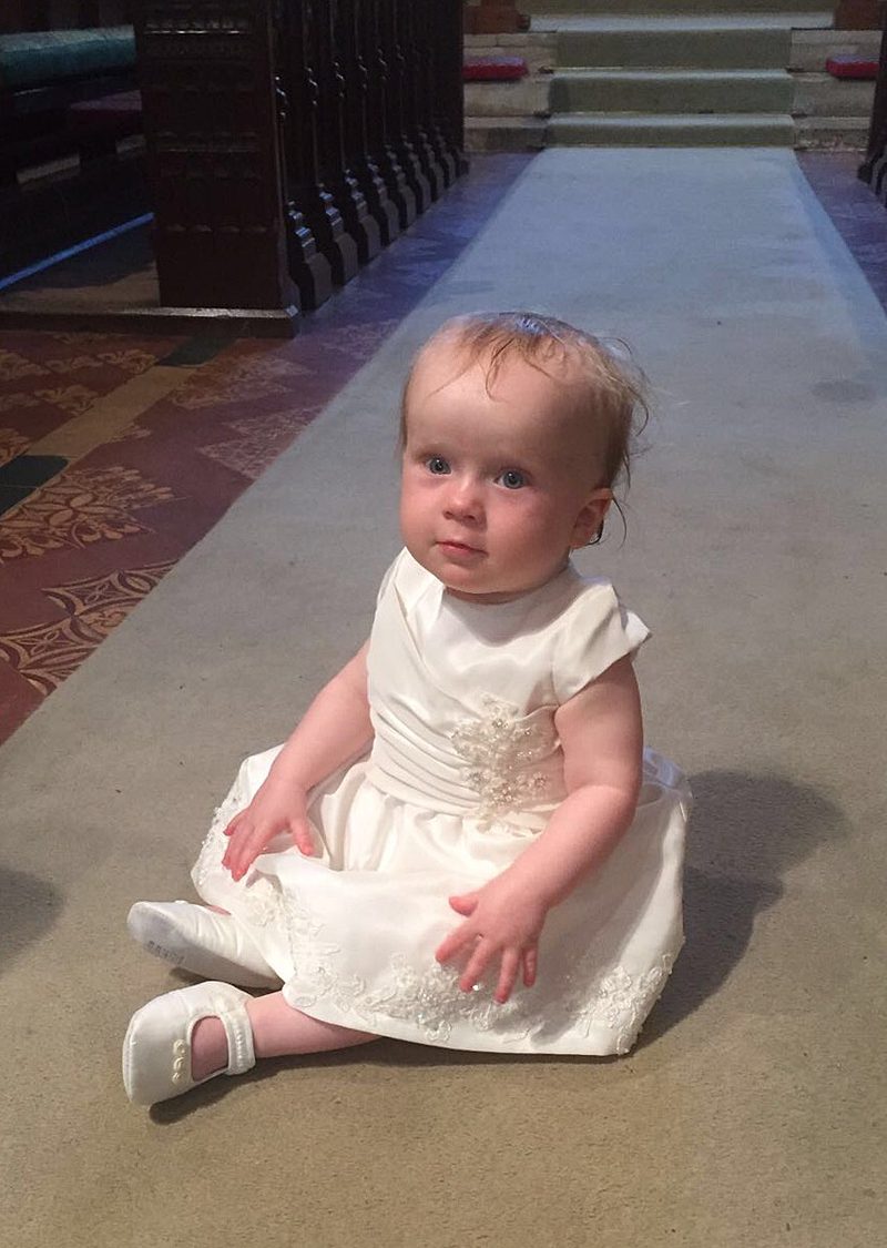 custom christening dress on baby in church