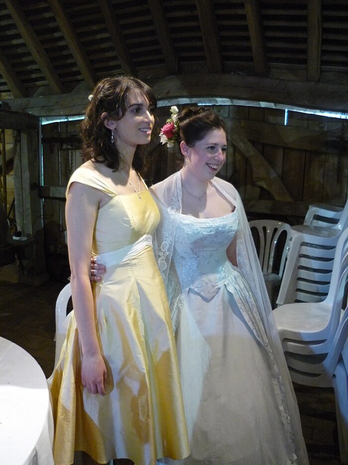 gold silk bridesmaid dress with sash with the bride in blue